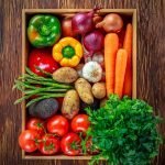 VARIETY OF COLORFUL VEGETABLES IN A BOX ON WOODEN TABLE.
